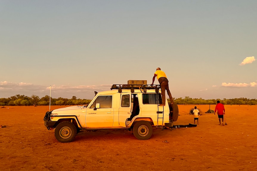 A white four wheel drive car parked on dirt at dusk