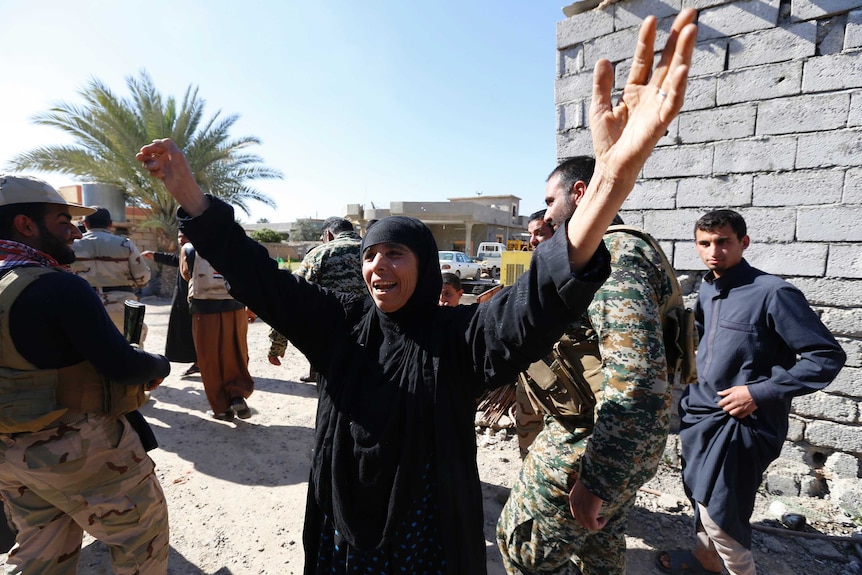 Residents celebrate the arrival of the Iraqi army and militia fighters in the town of al-Alam