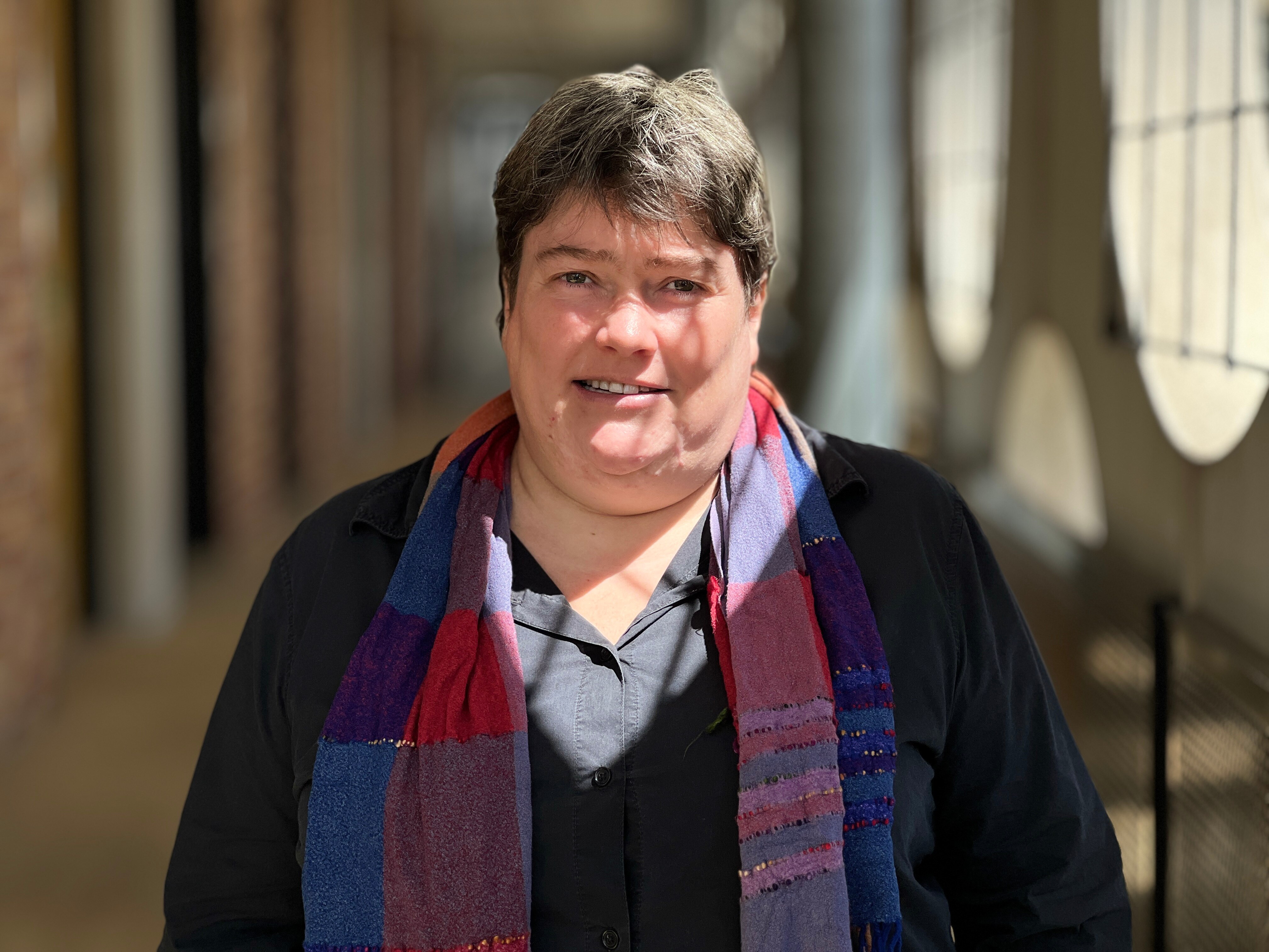 A woman wearing a black shirt and plaid scarf.
