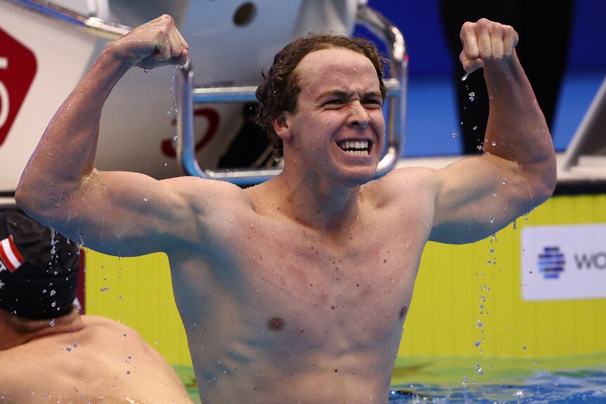 An Australian male swimmer flexes his arms as he celebrates winning gold medal at World Aquatics Championships.