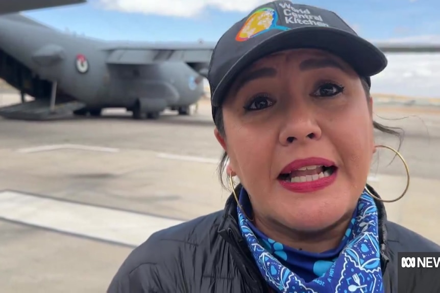 Aid worker Zomi Frankcom stands on the tarmac infront of a military airplane.