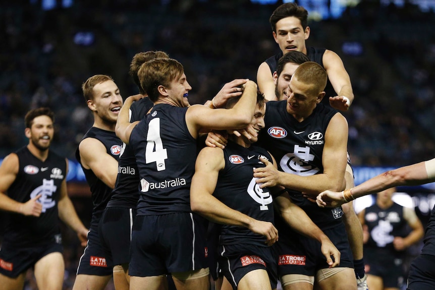 A group of happy AFL teammates get around a player who has just kicked a goal.