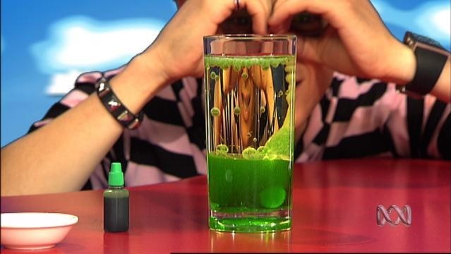 Person looks at drinking glass full of water and green gooey liquid