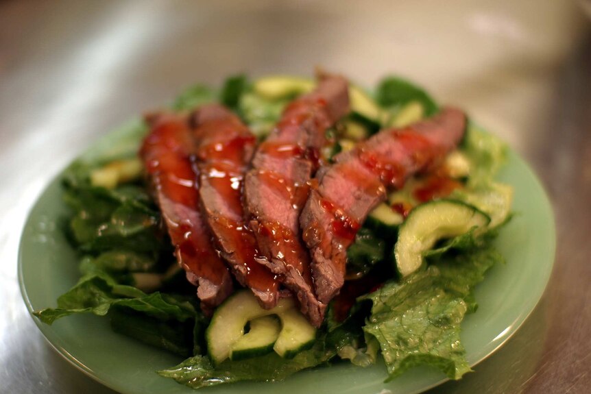 Flank steak salad served on a green plate.