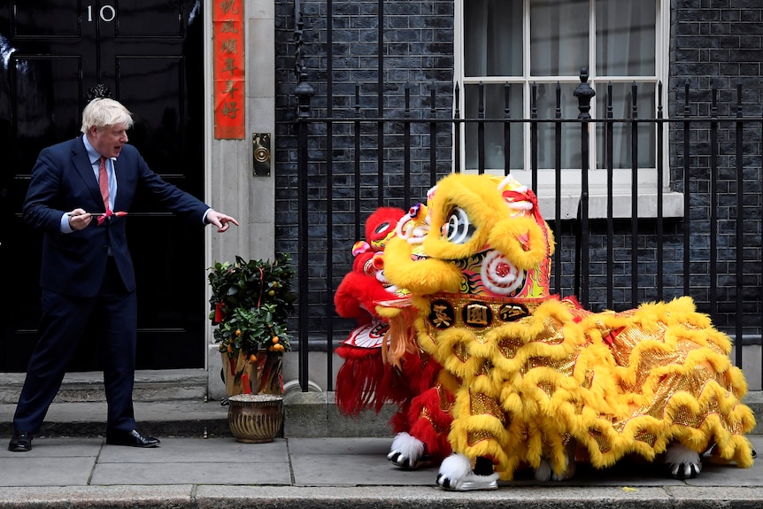 Boris Johnson points at two dragon puppets outside 10 Downing Street