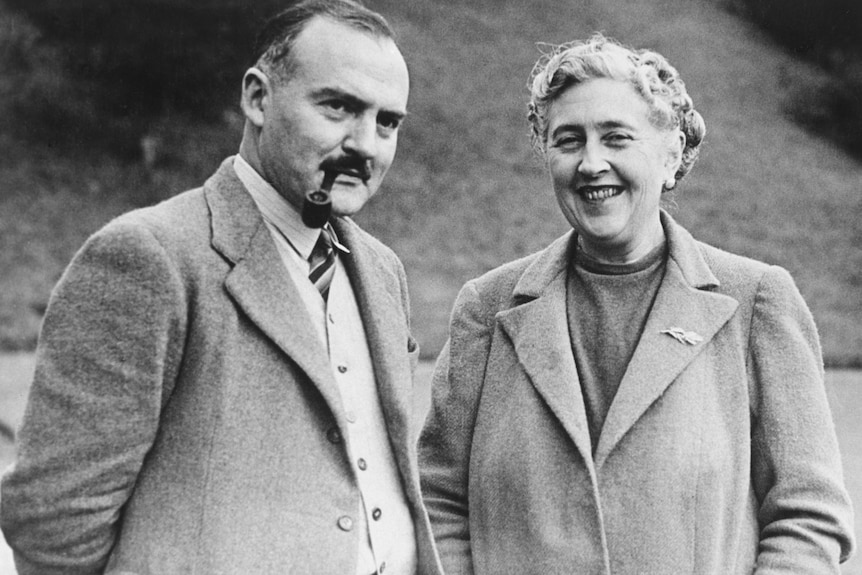 A black and white photo of Agatha Christie looking very happy with a man smoking a pipe