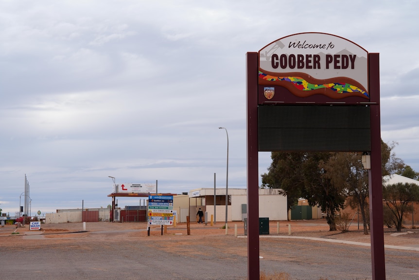 A photo showing a welcome to Coober Pedy sign with building in background