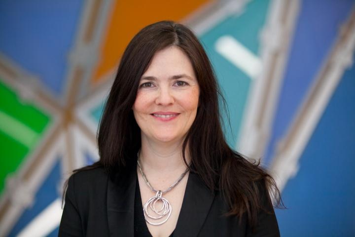 A woman poses against a colourful background for a portrait