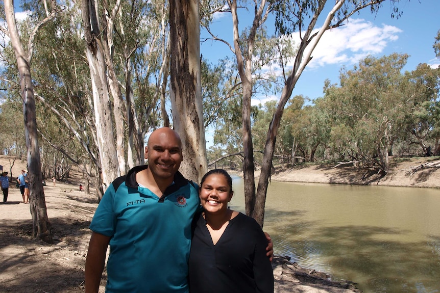 Two people standing near river