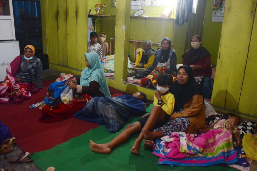 Villagers rest at a temporary shelter after evacuating their homes following the eruption of Mount Semeru.