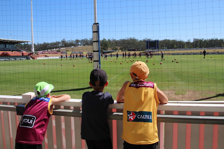 Young supporters lean on the field fencing to watch Brisbane Lions at training