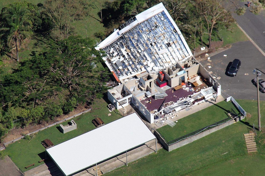 An aerial shot of a large building that has been torn apart by a cyclone.