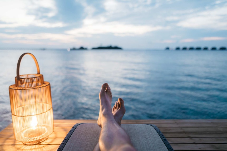 Legs on a pier with a light overlooking the water.