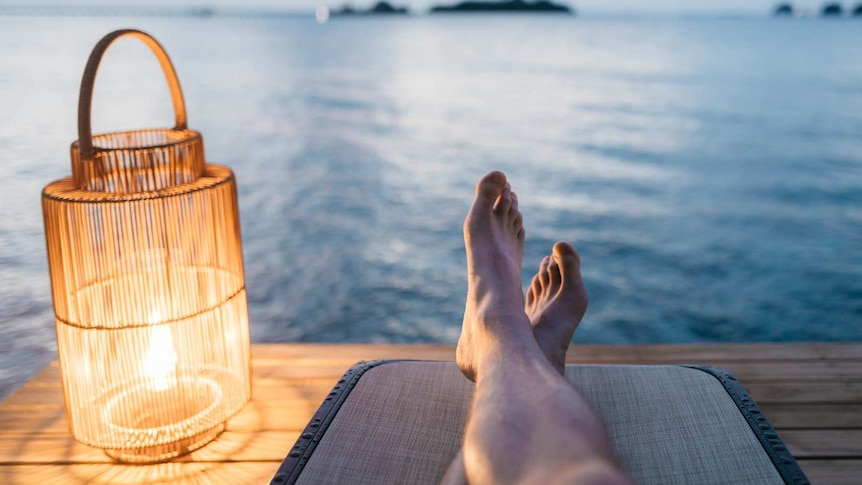 Legs on a pier with a light overlooking the water.