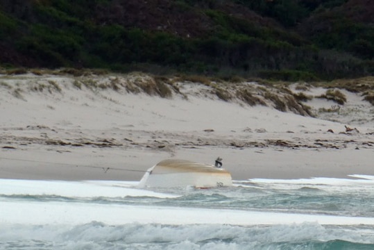 An upturned dinghy secured to the beach.