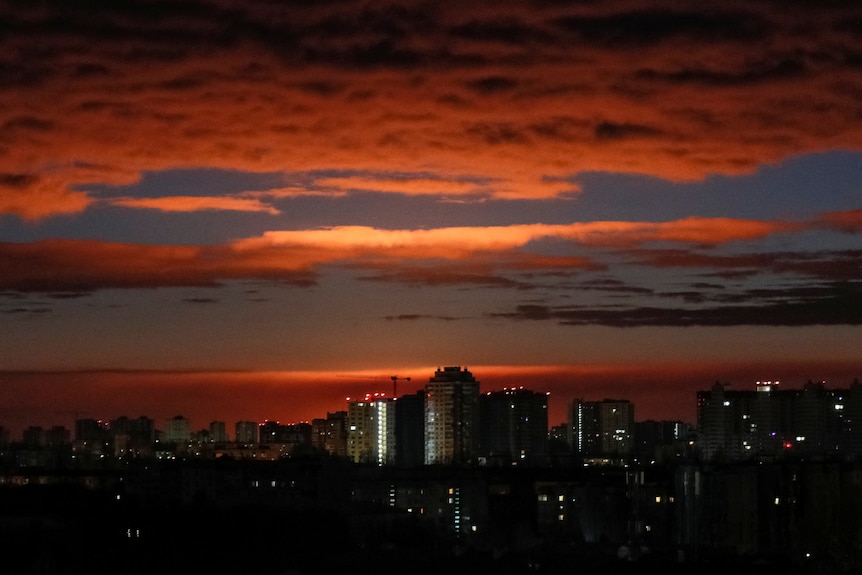 A large orange glow in the night sky above high-rise building in Kyiv