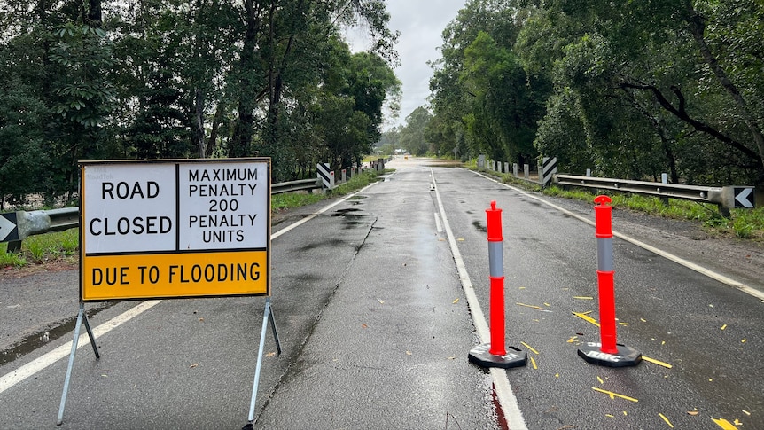 Signs warning Old Maroochydore Road, Forest Glen, closed on the Sunshine Coast, flooded road in the background