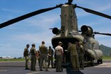 ADF personnel stand behind a Chinook helicopter.