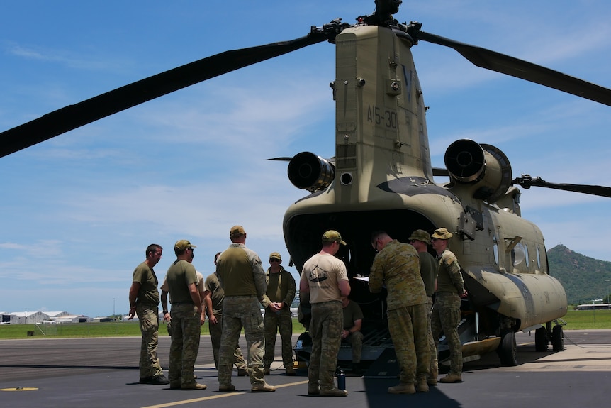 ADF personnel stand behind a Chinook helicopter.