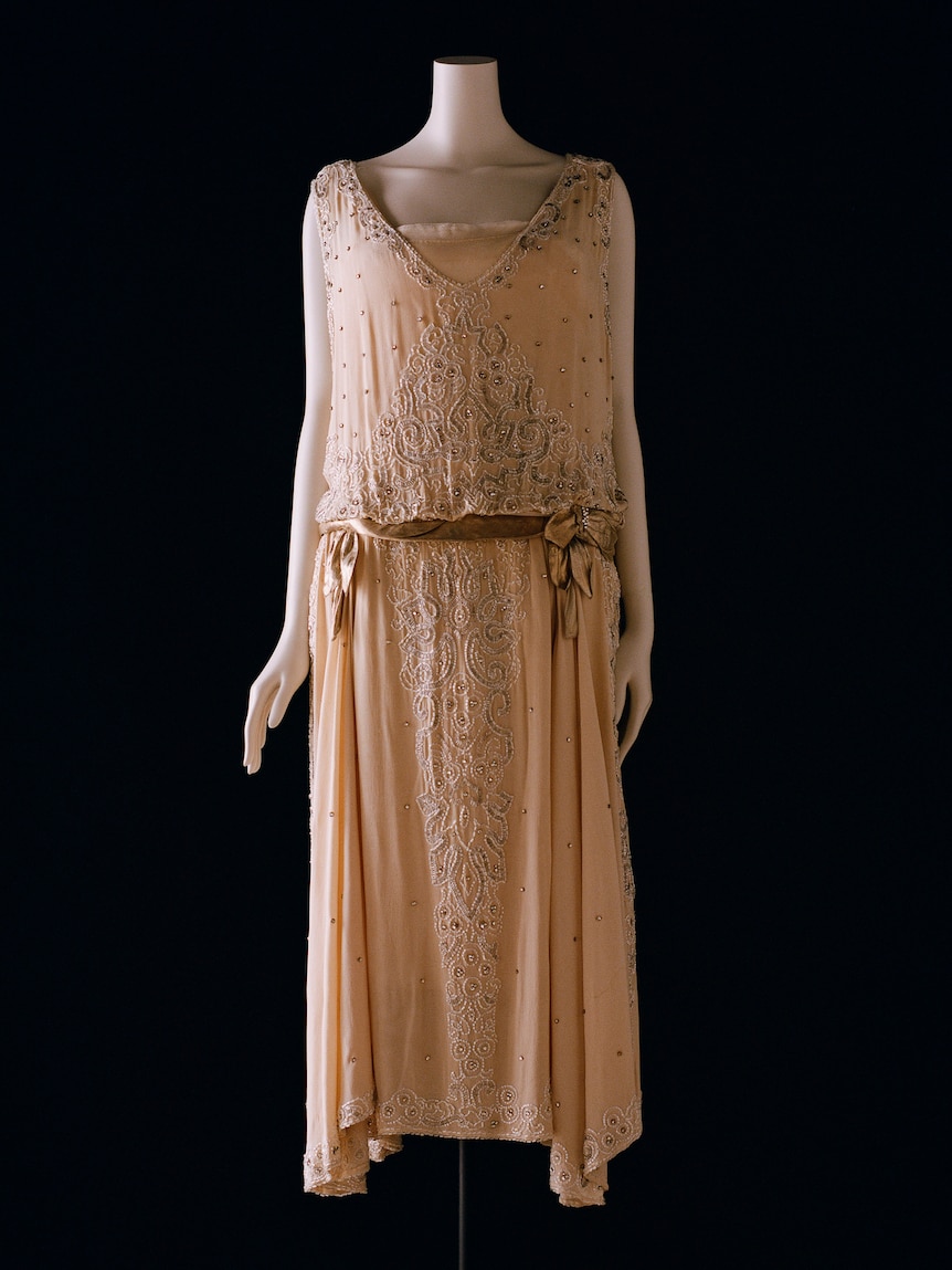 Fashion model in 1920s evening dress, pastel peach crepe bouderie embroidered with rhinestones