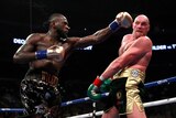 Deontay Wilder throws a punch with his left fist as Tyson Fury trys to avoid it.