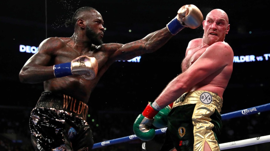 Deontay Wilder throws a punch with his left fist as Tyson Fury trys to avoid it.
