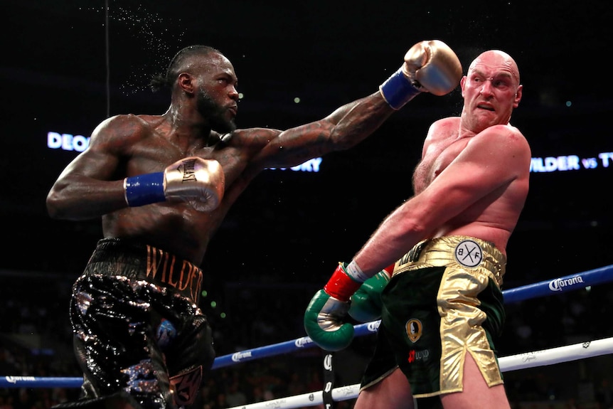 Deontay Wilder throws a punch with his left fist as Tyson Fury trys to avoid it.