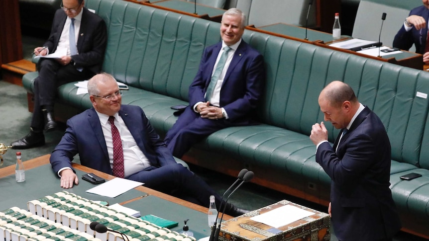 Scott Morrison and Michael McCormack laugh while Josh Frydenberg coughs in the House of Representatives