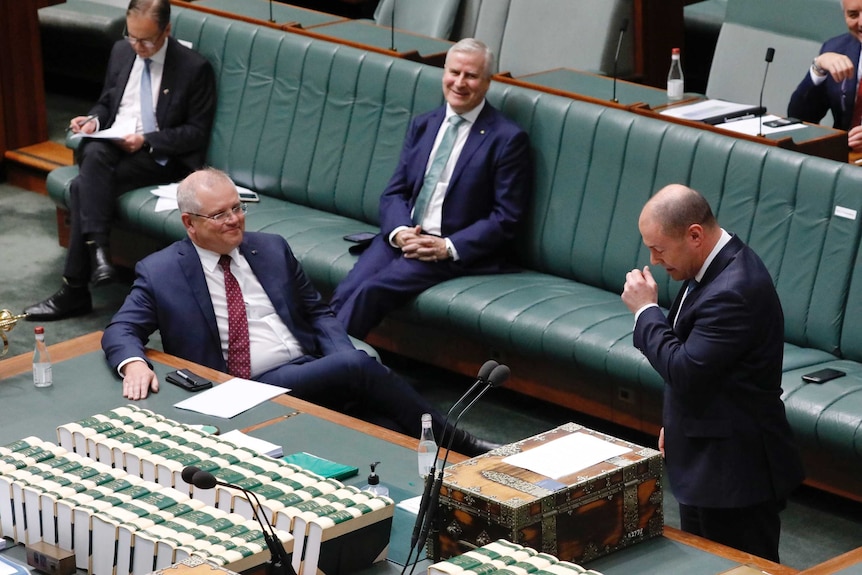 Scott Morrison and Michael McCormack laugh while Josh Frydenberg coughs in the House of Representatives