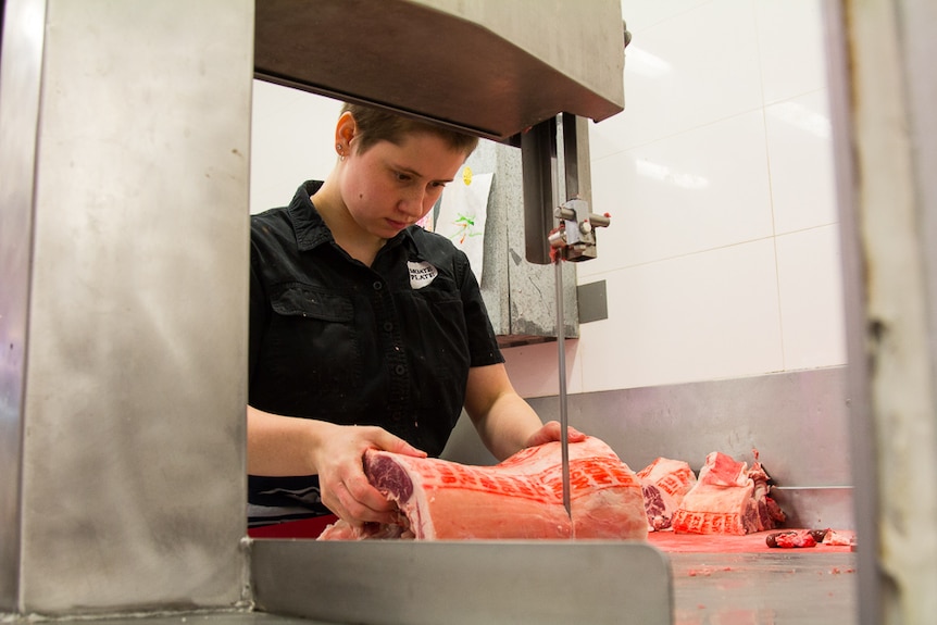 Apprentice butcher Sarah Wadland using a meat band saw.