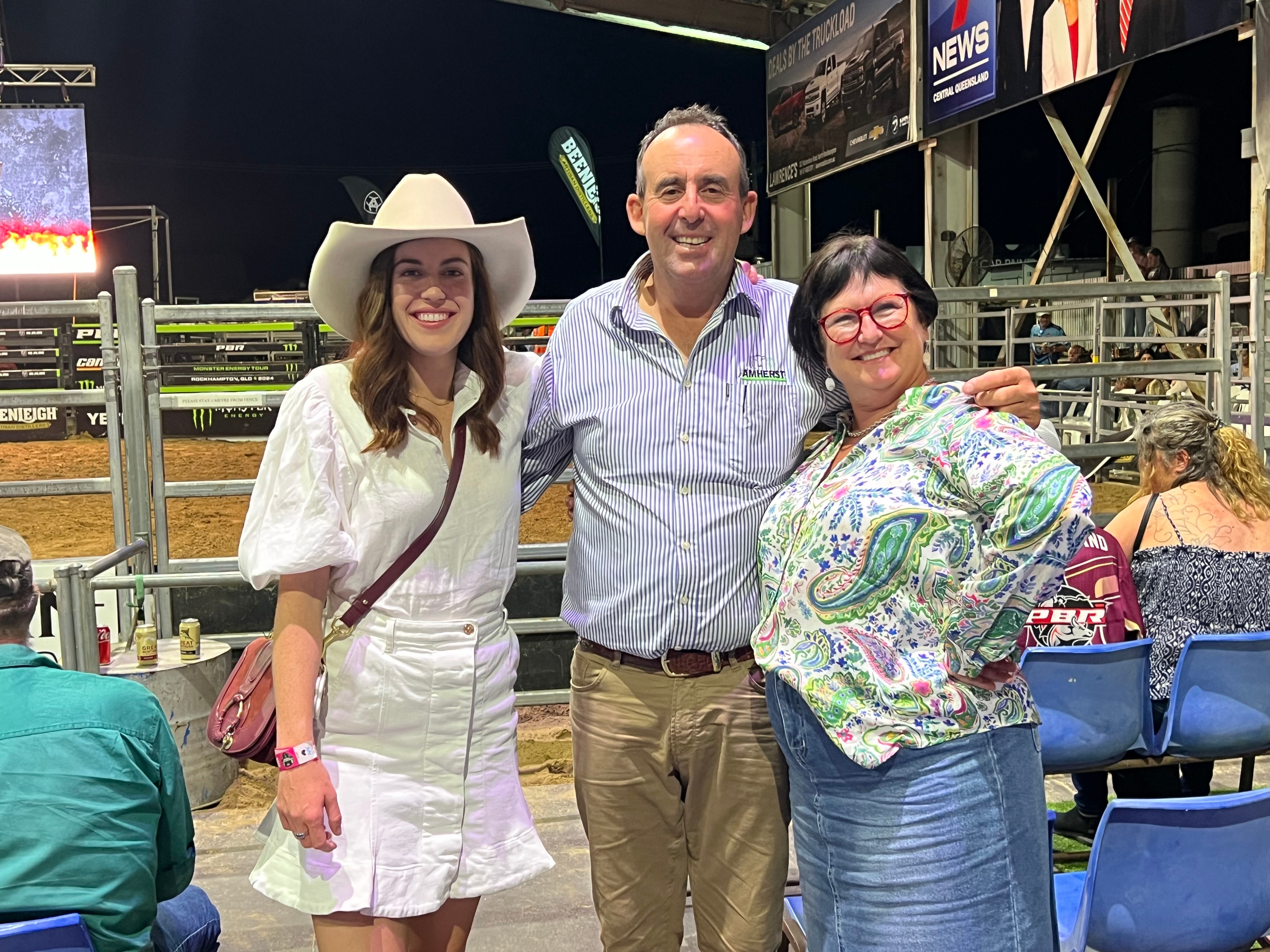 a man stands with his arms around two women