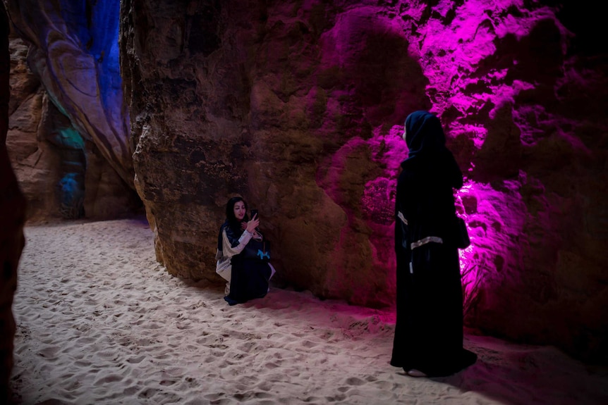 A woman takes a photo of a friend in Saudi Arabia.