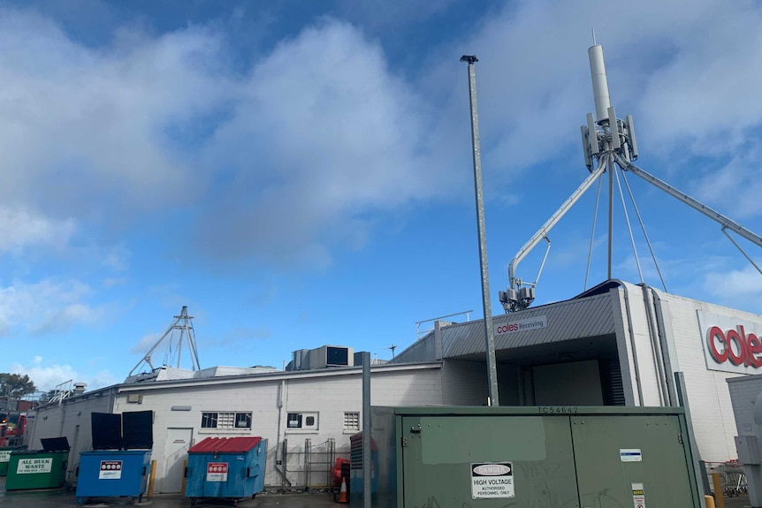 The back of a supermarket with two phone towers above it, one damaged and one not