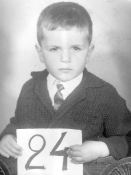 Postecoglou as a five-year-old, holding up his immigration number on arrival in Melbourne from Athens by boat in 1970.