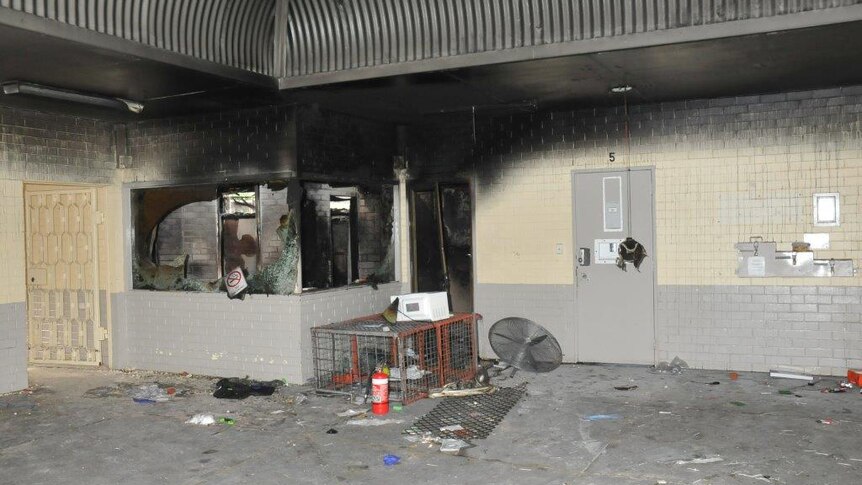 Fire damage at Greenough Regional Prison with walls scorched black, windows smashed and debris lying on the floor.