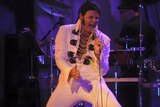 A man dressed up as Elvis performing on stage