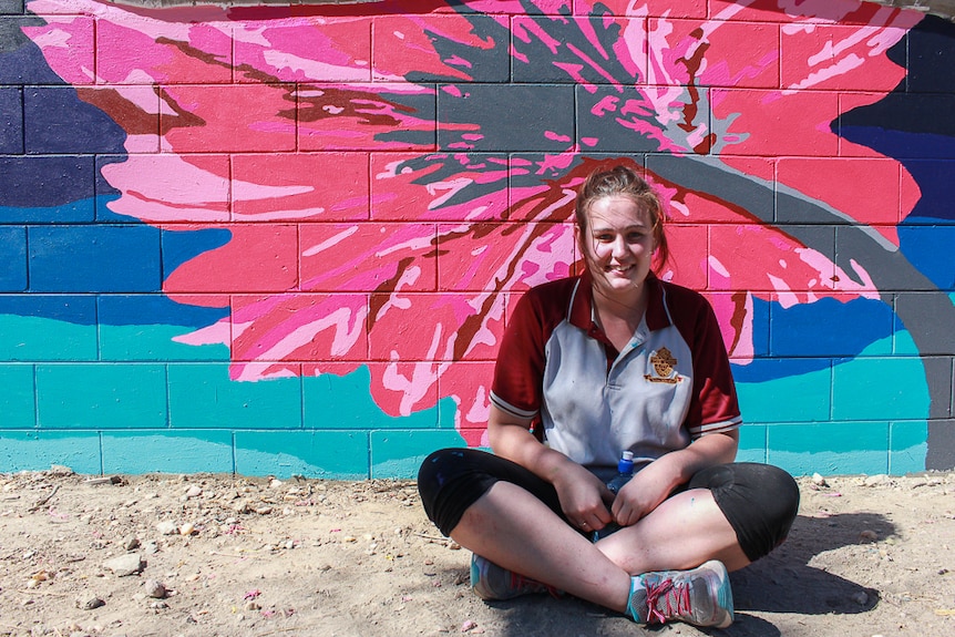 Tiarnah Carroll sits in front of the mural at Hughenden State School