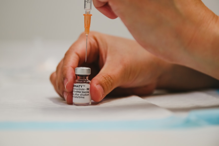 A needle and a vial of COVID-19 Pfizer vaccine.