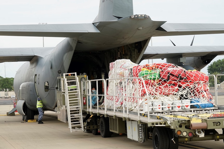 A C-130J Herculus transport aircraft, with a large amount of medical supplies and equipment about to be loaded in.