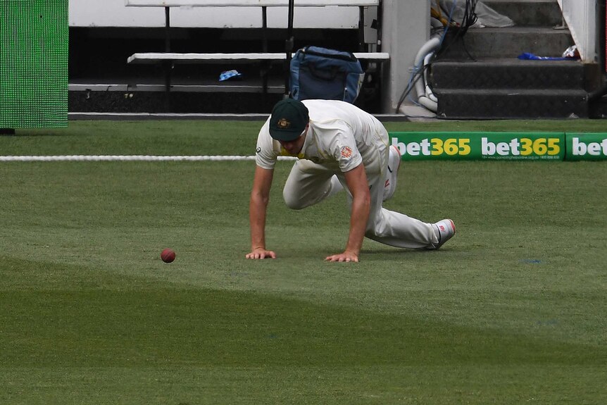 Australia bowler Pat Cummins crawls after a cricket ball while fielding on the boundary during a Test at the MCG.