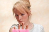 Woman at desk with arm outstretched with pink sticky note saying 'no' on on her palm