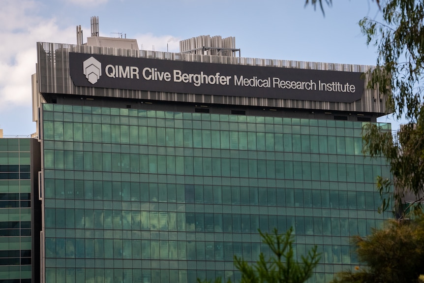 A large glass building with a sign labelling it QIMR Clive Bergofer Medical Research Institute.