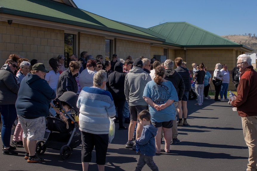 A crowd of dozens of people outside a medical centre.