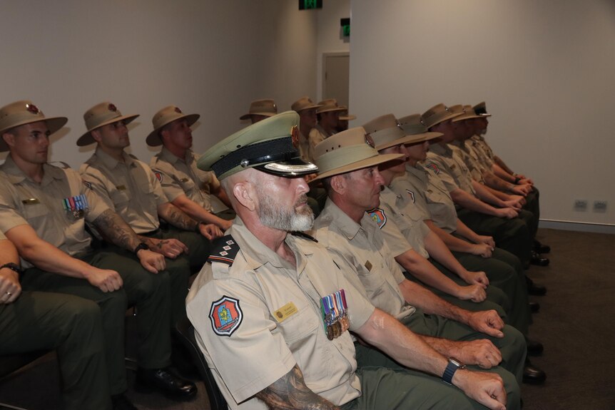 Recruits sit with their first resting on their knees at a graduation day for NT Corrections.