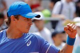 Tennis player Alex de Minaur, wearing a blue shirt and cap, clenches his fist during a tennis match.