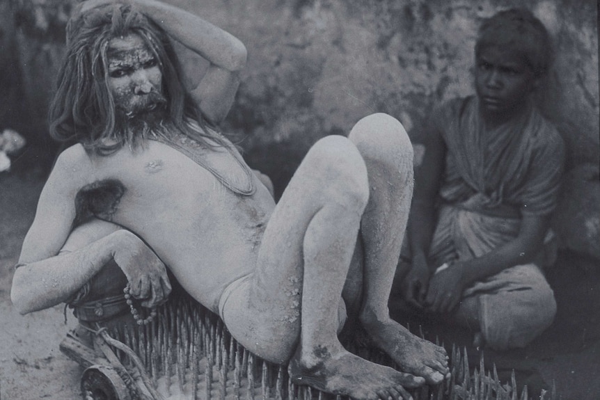 Indian holy man lies on a bed of nails.
