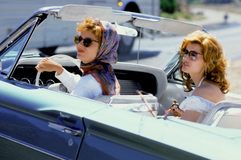 A film still of Geena Davis, Susan Sarandon and Brad Pitt driving in a blue convertible, Sarandon at wheel.