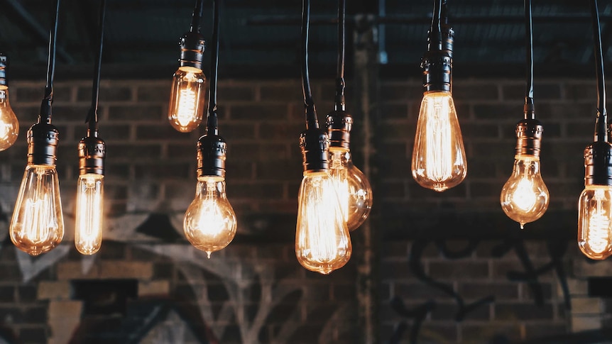 A series of hanging light bulbs with a brick wall in the background.