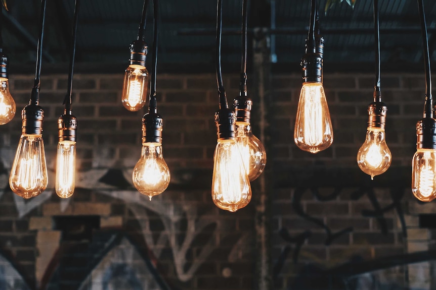 A series of hanging light bulbs with a brick wall in the background.