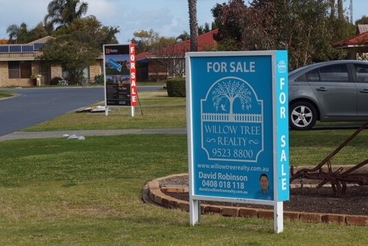 Two for sale signs on laws outside houses in Perth's south.